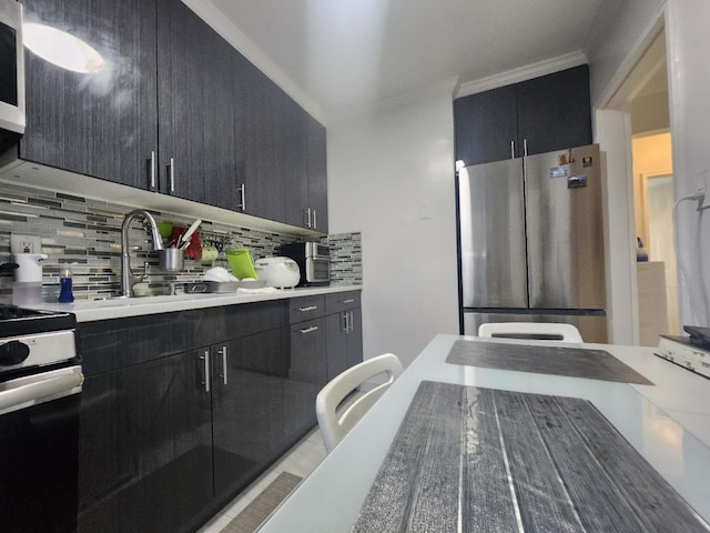 kitchen with decorative backsplash, white range oven, crown molding, sink, and stainless steel refrigerator