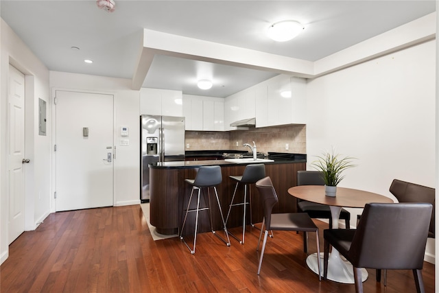 kitchen featuring backsplash, extractor fan, sink, stainless steel fridge with ice dispenser, and white cabinetry