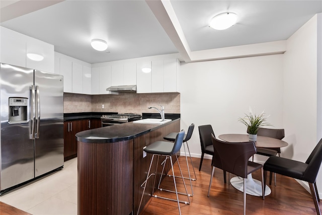 kitchen featuring dark brown cabinetry, white cabinetry, stainless steel appliances, extractor fan, and decorative backsplash