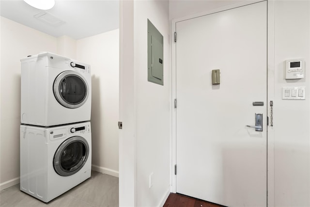 washroom with stacked washing maching and dryer and electric panel