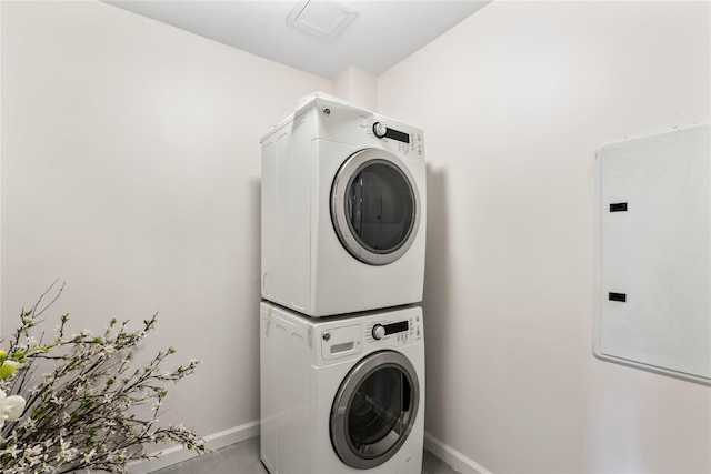 laundry room with electric panel and stacked washer / drying machine