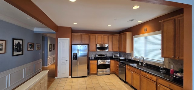 kitchen with sink, stainless steel appliances, tasteful backsplash, dark stone counters, and light tile patterned flooring