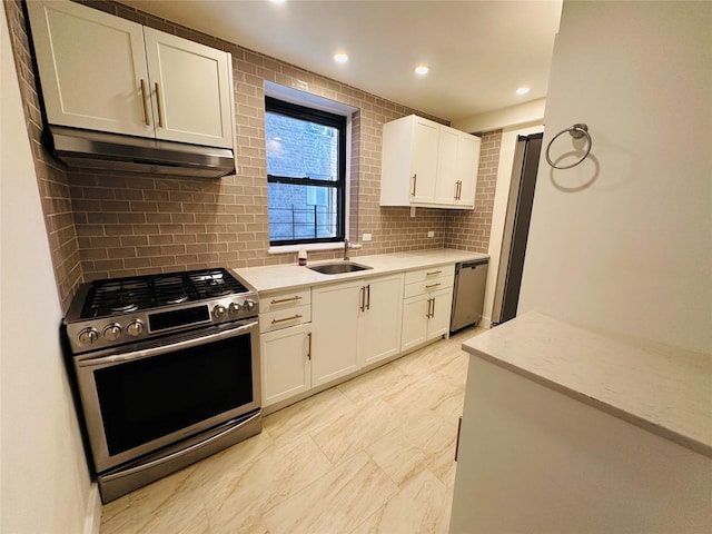 kitchen featuring decorative backsplash, appliances with stainless steel finishes, light stone countertops, sink, and white cabinets