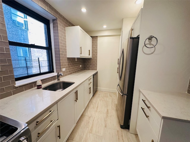 kitchen featuring sink, stainless steel appliances, light stone counters, backsplash, and white cabinets