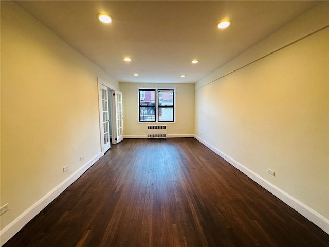 empty room featuring dark wood-type flooring, radiator, and french doors