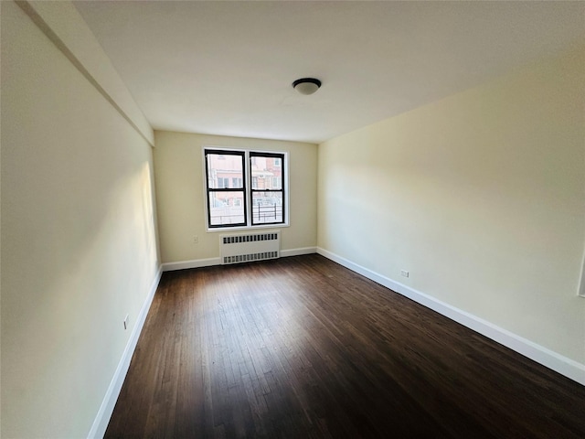 empty room with dark hardwood / wood-style flooring and radiator heating unit