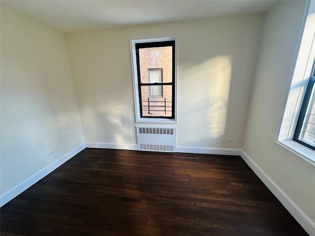 spare room featuring radiator and dark wood-type flooring