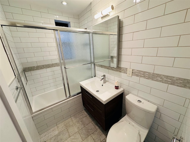 full bathroom with vanity, toilet, tile walls, and enclosed tub / shower combo