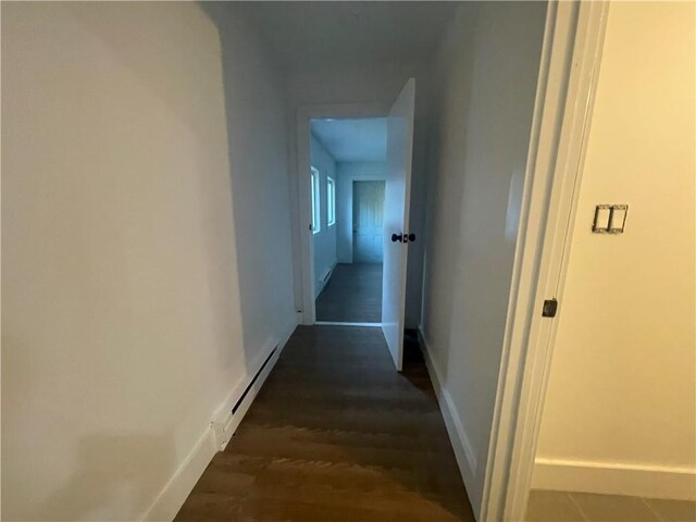 hallway with a baseboard heating unit and dark hardwood / wood-style flooring