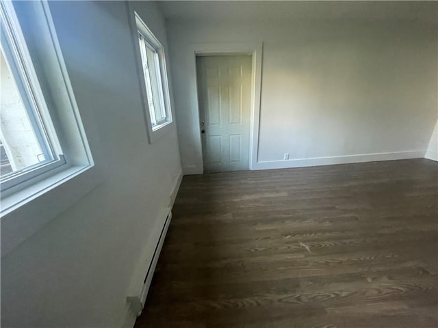 corridor with a baseboard radiator, dark hardwood / wood-style floors, and plenty of natural light