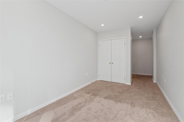 unfurnished bedroom with light colored carpet and a closet