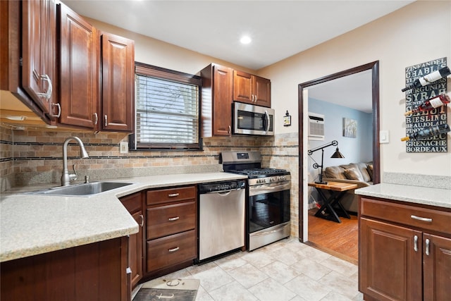 kitchen with an AC wall unit, decorative backsplash, sink, appliances with stainless steel finishes, and light tile patterned floors