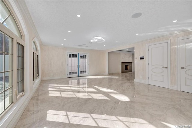 unfurnished living room with a premium fireplace, french doors, a textured ceiling, and ornamental molding