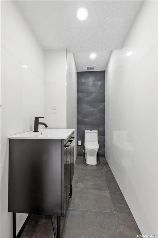 bathroom with vanity, toilet, and tile walls