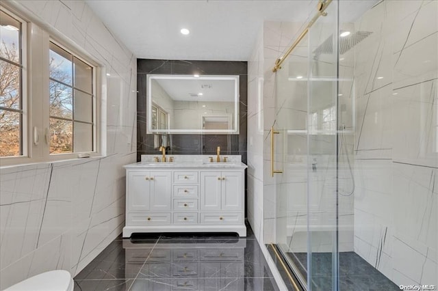 bathroom with vanity, an enclosed shower, and tile walls