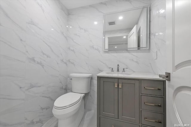 bathroom featuring vanity, toilet, and tile walls