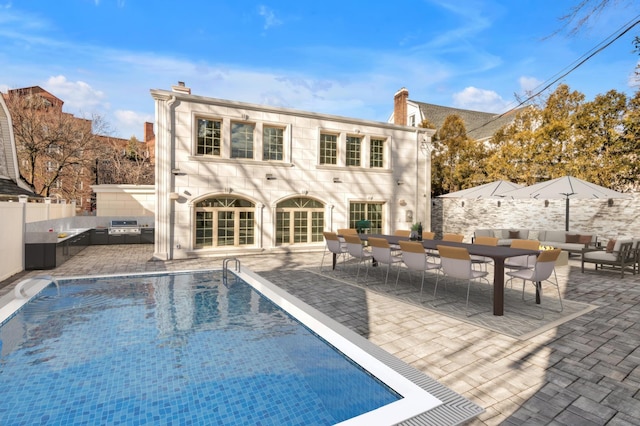 rear view of property with a fenced in pool and a patio