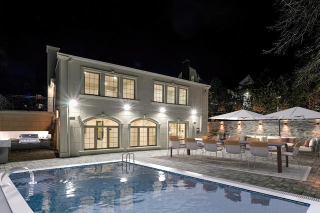 back house at night featuring a patio area and exterior bar