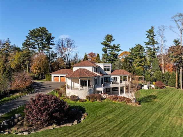 back of property with a yard, a balcony, and a garage