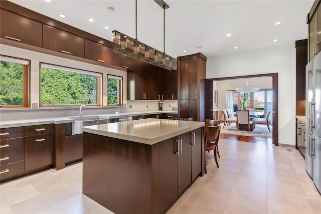 kitchen with a kitchen bar, dark brown cabinets, sink, pendant lighting, and a kitchen island