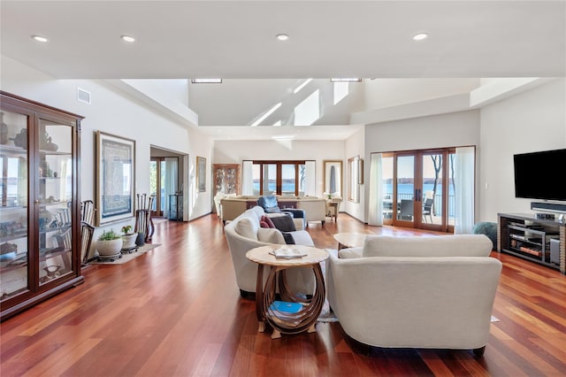 living room featuring wood-type flooring, a towering ceiling, and french doors