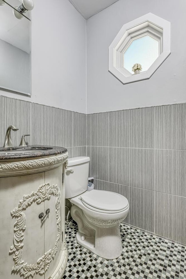 bathroom featuring tile patterned floors, vanity, toilet, and tile walls