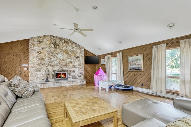 living room with wood walls, vaulted ceiling, ceiling fan, a fireplace, and wood-type flooring