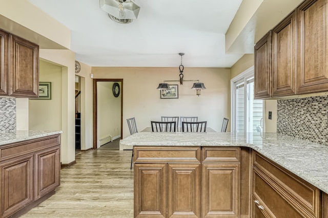 kitchen featuring kitchen peninsula, decorative light fixtures, tasteful backsplash, and a baseboard radiator