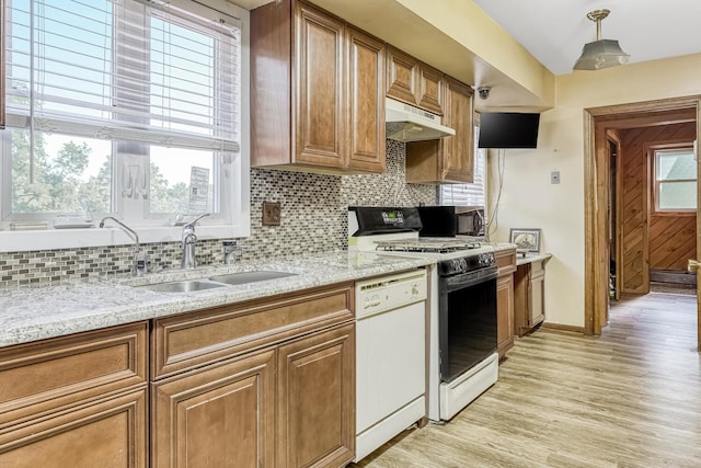 kitchen featuring dishwasher, backsplash, sink, gas range oven, and light stone counters