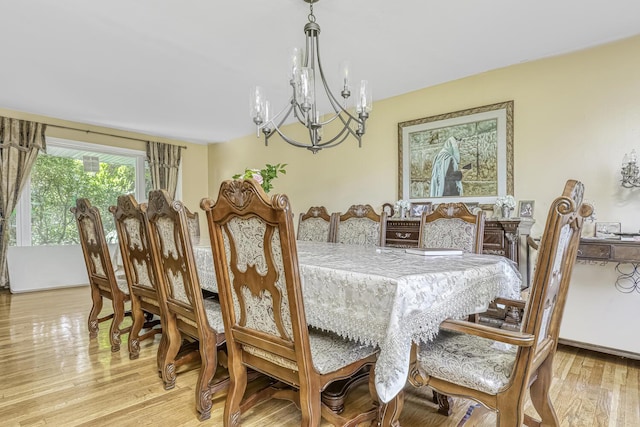 dining space with light hardwood / wood-style flooring and a notable chandelier