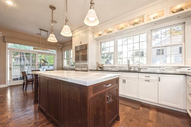 kitchen featuring pendant lighting, white cabinets, built in fridge, and dark stone counters