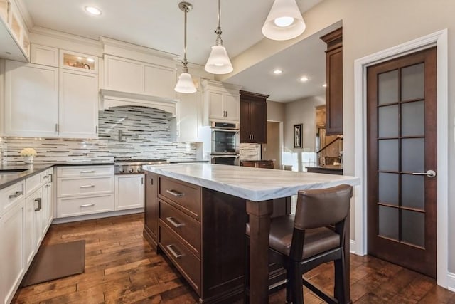 kitchen with a breakfast bar, decorative light fixtures, dark hardwood / wood-style floors, a kitchen island, and backsplash