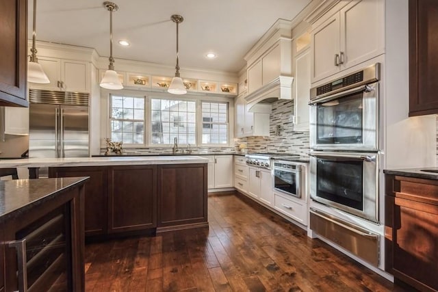 kitchen with appliances with stainless steel finishes, dark hardwood / wood-style floors, sink, decorative backsplash, and hanging light fixtures