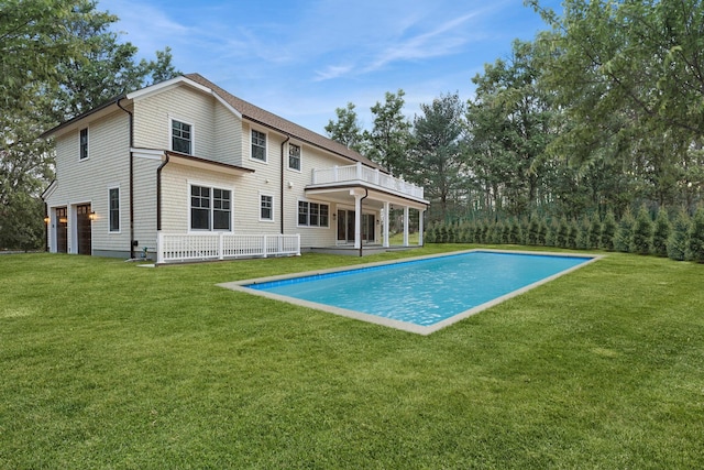 back of property featuring a balcony, a garage, and a lawn