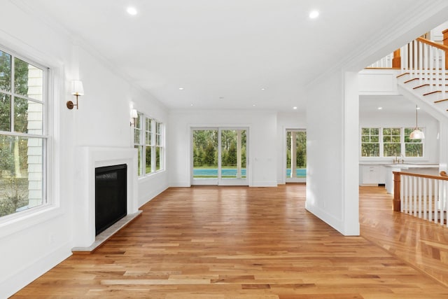 unfurnished living room with crown molding and a healthy amount of sunlight