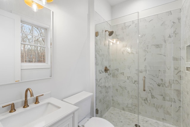 bathroom featuring a shower with door, vanity, and toilet