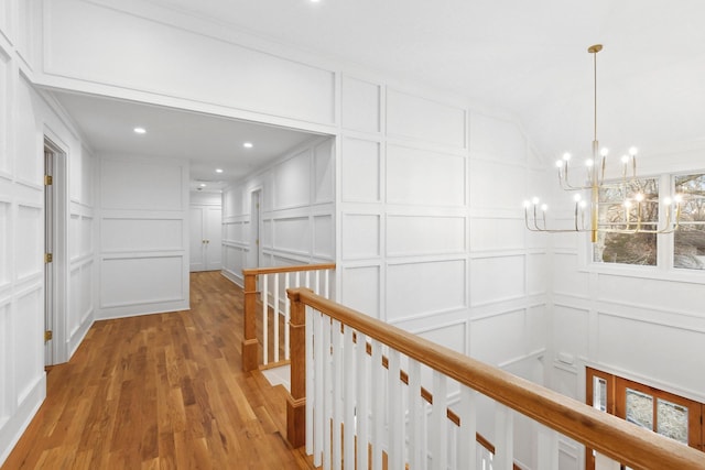 corridor with hardwood / wood-style floors and a notable chandelier