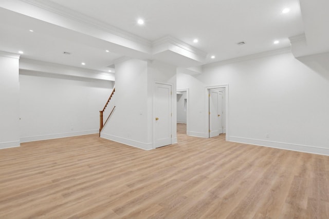 basement with ornamental molding and light hardwood / wood-style floors