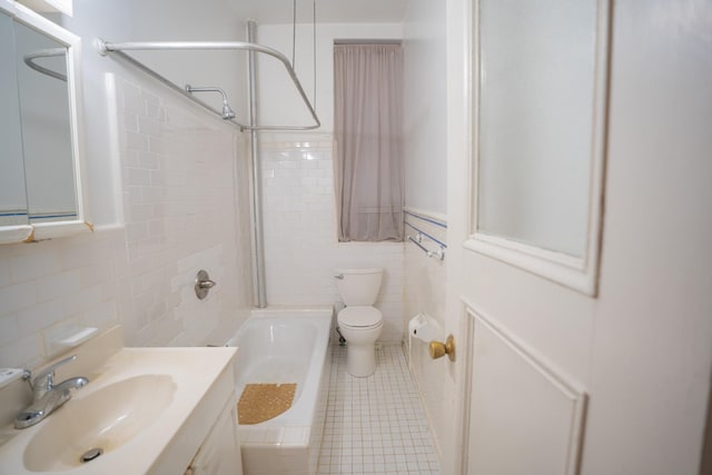 full bathroom with toilet, vanity, tile patterned flooring, tile walls, and shower / bath combination