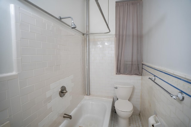 bathroom with tile walls, toilet, and tiled shower / bath