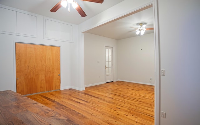 spare room featuring a ceiling fan, light wood-type flooring, and baseboards