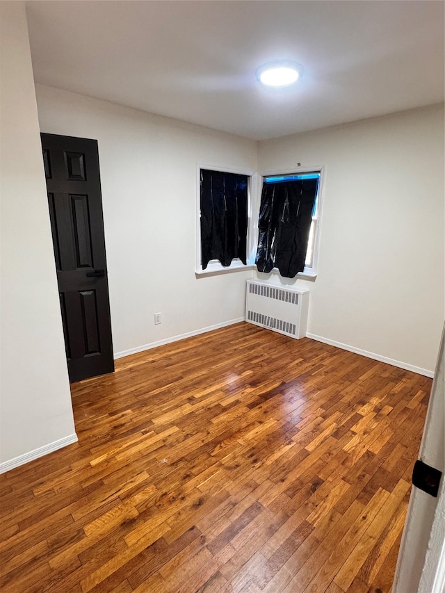 unfurnished room featuring wood-type flooring and radiator