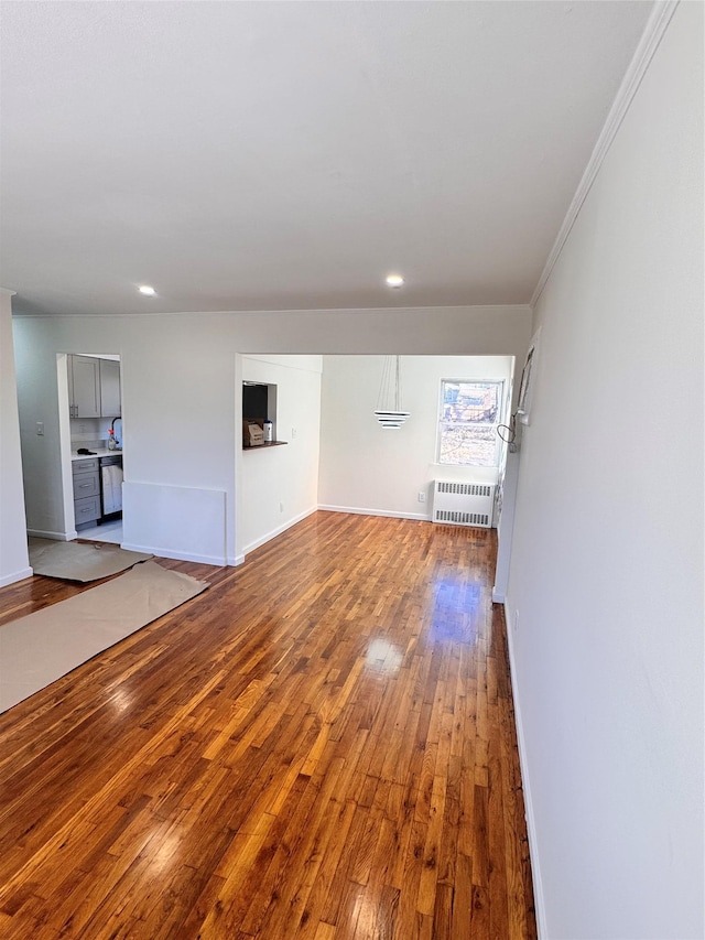 unfurnished living room featuring radiator and hardwood / wood-style flooring