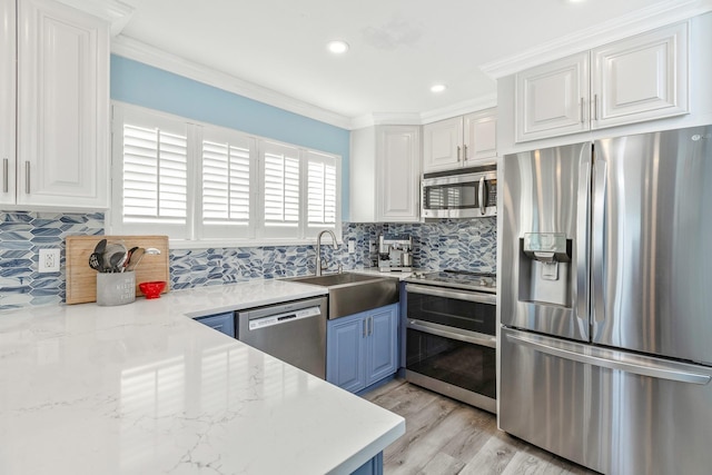 kitchen with sink, crown molding, white cabinetry, stainless steel appliances, and light stone countertops