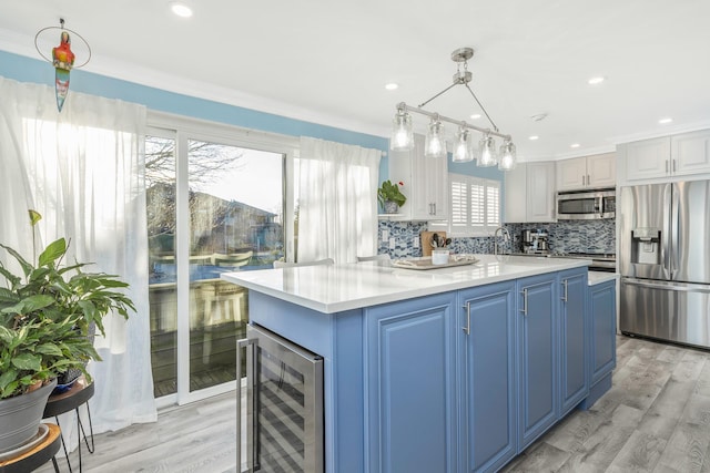 kitchen featuring pendant lighting, white cabinetry, stainless steel appliances, blue cabinets, and beverage cooler