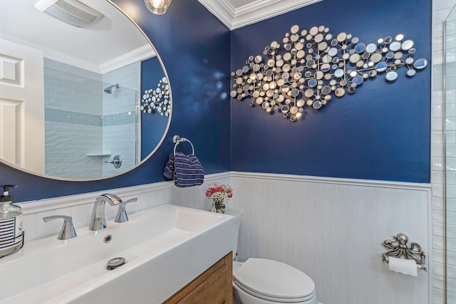 bathroom with ornamental molding, toilet, vanity, and a tile shower