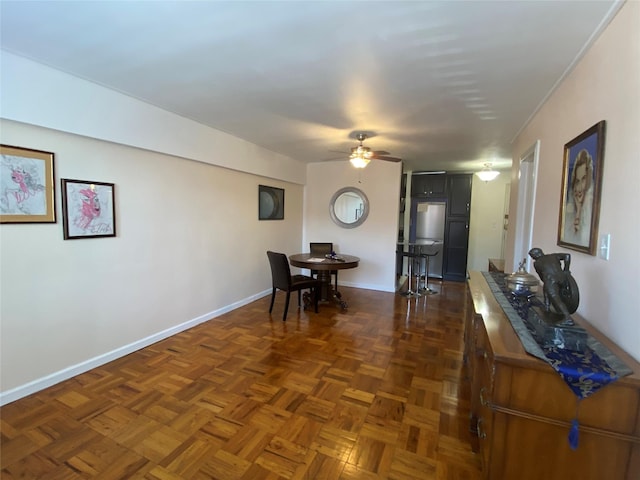 dining space with ceiling fan and dark parquet flooring