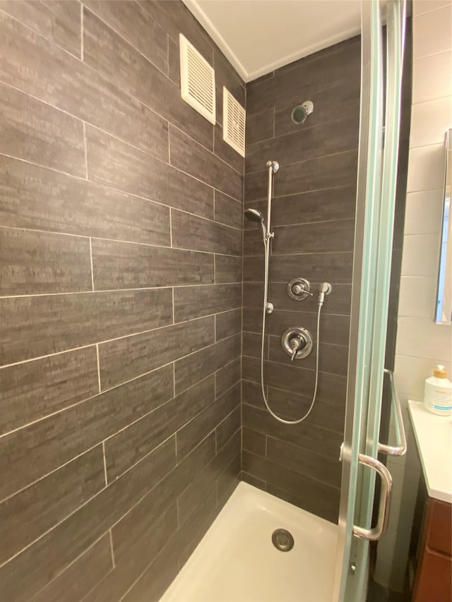 bathroom featuring a shower with door and vanity