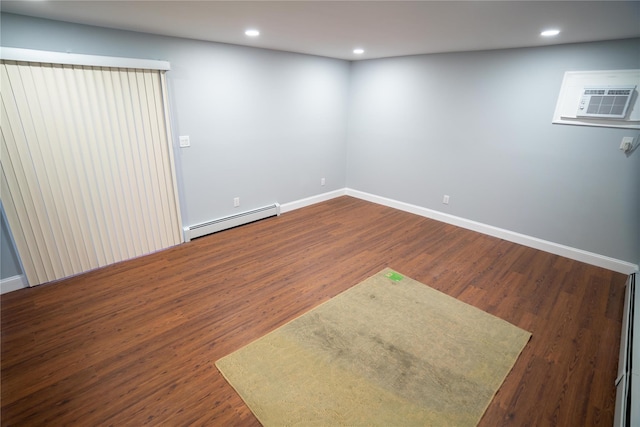 spare room with an AC wall unit, baseboard heating, and dark wood-type flooring