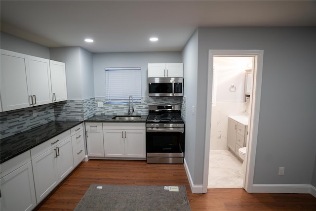 kitchen with decorative backsplash, appliances with stainless steel finishes, dark hardwood / wood-style flooring, sink, and white cabinetry